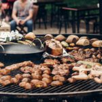 grilled meat and vegetables mushrooms. roasting beef pork on big grill, open kitchen, street food festival. cooking smoked juicy ribs potatoes bbq and bread. summer picnic